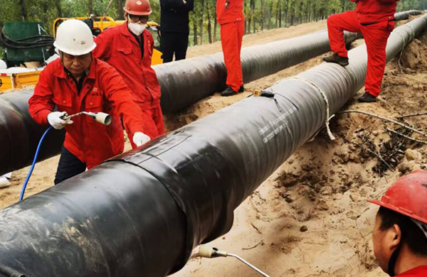 Heat shrink sleeve being installed over pipeline girth weld — field joint coating process