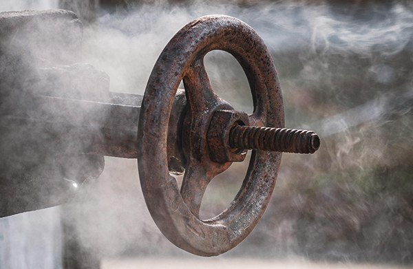 Corroded flange and valve on pipeline — irregular surfaces trap moisture, accelerating corrosion