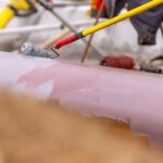 Solvent-free epoxy primer being applied on pipeline weld joint — high-solid corrosion protection coating for field joint coating