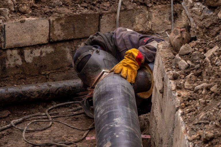 Installation of a large-diameter concrete or steel sewage pipeline in an excavated trench, illustrating underground wastewater infrastructure